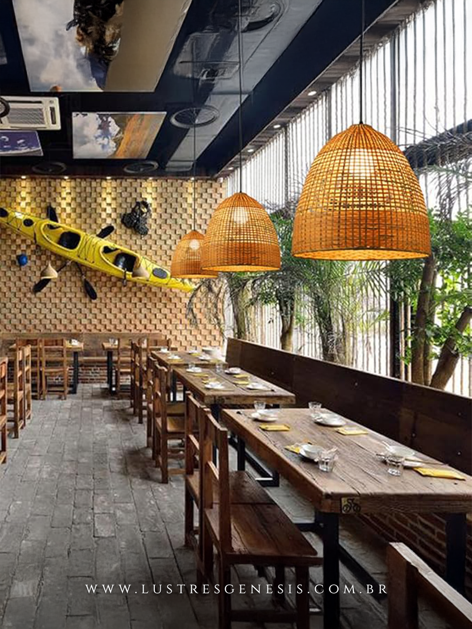 Pendentes rústicos de bambu Trace Ø35cm instalados em área gourmet com mesas de madeira, ambiente decorado com parede de tijolos e caiaque amarelo.